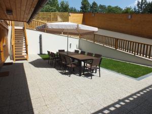 a patio with a table and chairs and an umbrella at Chaty pod Sokolím Hřbetem in Česká Ves