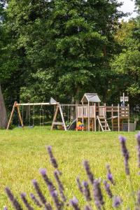 a playground in a park with purple flowers in the foreground at Morski Las in Ustronie Morskie
