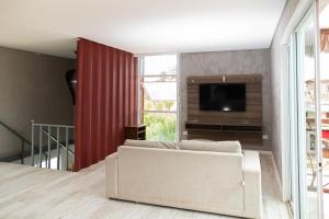 a living room with a white couch and a flat screen tv at Kicoh - Kite Community House in Itarema