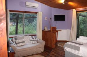 a bedroom with purple walls and a bed and a couch at Estero El Claro Hotel y Cabañas in Pucón