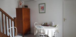 a dining room with a table and white chairs at La cornouillère in Champau