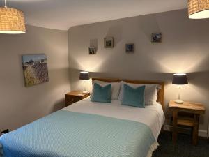 a bedroom with a large bed with blue pillows at Blue Sky Cottage in Matlock