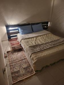 a bed with blue pillows and a rug in a room at your cute house in Salé