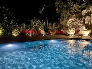 a swimming pool at night with chairs and umbrellas at Gite 24 in Beaumont +7 photos