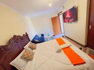a bedroom with a large bed and a blue couch at GREENFIELD STUDlO DONHOLM in Nairobi +16 photos