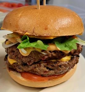 a hamburger on a bun with cheese and lettuce at Camping le beauvillage Lauzerte in Lauzerte