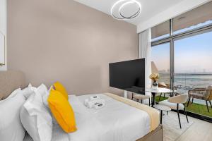 a bedroom with a bed with yellow pillows and a television at Waves - Modern & Vibrant Studio With Skyline View in Sabkhah