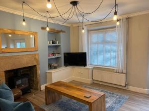 a living room with a fireplace and a tv at Blue Sky Cottage in Matlock