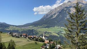 a village on a hill with a mountain in the background at Tgesa communala Mon in Mons