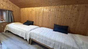 two beds in a room with wooden walls at Tgesa communala Mon in Mons