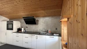 a kitchen with white cabinets and a white refrigerator at Tgesa communala Mon in Mons