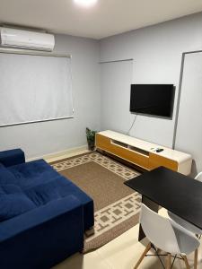a living room with a blue couch and a tv at Apartamento no centro de Cuiaba até 3 pessoas in Cuiabá