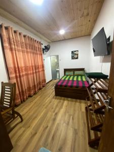 a room with a bed and a tv and wooden floors at The Ceylon Olive Resort in Katunayaka