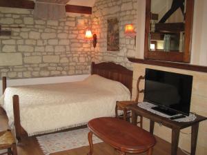 a bedroom with a bed and a desk with a television at Le grenier d'alice in Thurageau