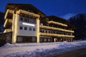 a building covered in lights in the snow at Hotel Rododendro Val di Fassa in Campitello di Fassa