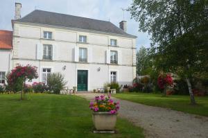 a large white house with flowers in the yard at La maisons des tilleuls in Thurageau