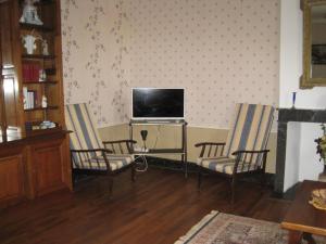 a living room with two chairs and a television at La maisons des tilleuls in Thurageau