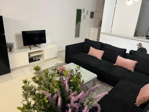 a living room with a black couch and a tv at Lavender Home in Volos