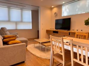 a living room with a couch a table and a tv at ura アルコバレーノ奉還町 in Okayama