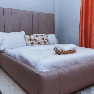 a large bed with white sheets and a basket on it at Bethany Cushy Home Ltd in Kisii