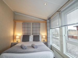 a bedroom with a bed with two pillows and two windows at Iona Lodge in Fort William