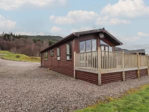 a small wooden cabin with a fence in front of it at Iona Lodge in Fort William