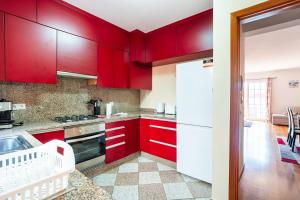 a red kitchen with white appliances and red cabinets at GuestReady - Alluring island retreat in Santa Cruz