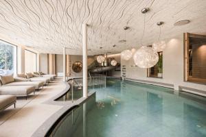 a swimming pool in a building with a lobby at Excelsior Dolomites Life Resort in San Vigilio Di Marebbe