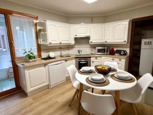a kitchen with white cabinets and a table and chairs at Villa Yoli, céntrico con plaza de garaje in Avilés