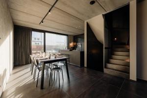 a dining room with a table and chairs and a staircase at Coliving - Bord de Meuse - L'échappée Mosane in Oupeye