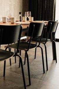 a dining table with black chairs and a table with wine glasses at Coliving - Bord de Meuse - L'échappée Mosane in Oupeye