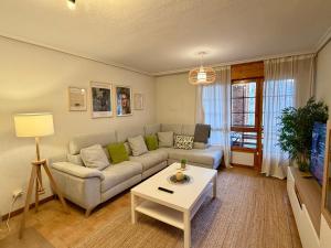a living room with a couch and a table at Villa Yoli, céntrico con plaza de garaje in Avilés