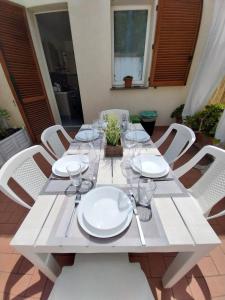 a white table with white plates and glasses on it at La casa accanto in Rio nellʼElba