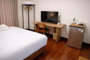 a bedroom with a desk with a television and a bed at Family Hostel in Chiang Rai