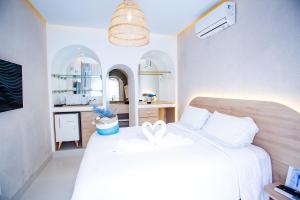 a bedroom with a white bed and a kitchen at D'Blue Búzios Hotel Boutique in Búzios