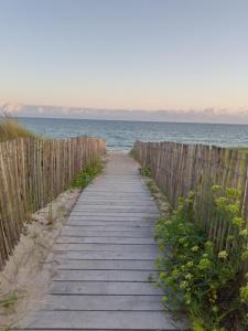 a wooden path leading to the ocean on a beach at Chambre d'Hôtes à Bopérec in Nostang