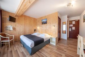 a bedroom with a bed and a desk and a chair at Hotel De La Route Verte in Gérardmer