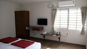 a bedroom with a bed and a television and a window at Rams Inn in Krishnagiri +7 photos