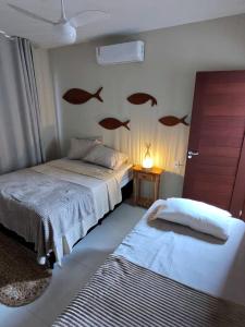 a bedroom with two beds with fish on the wall at Kite House Lençóis II in Santo Amaro +52 photos