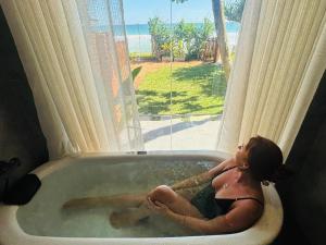a woman sitting in a bath tub in a window at La Brisa By Harry Beach Villa in Dickwella +71 photos