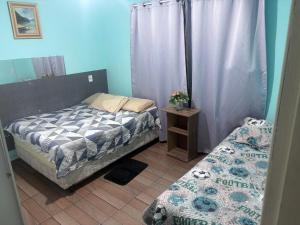 a bedroom with two twin beds and a table with a bedskirts at Casa aconchegante in Palhoça