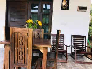 a wooden table with chairs and a vase with yellow flowers at Diyana Cottage in Sigiriya