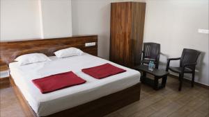 a bedroom with a bed with two red towels on it at Rams Inn in Krishnagiri