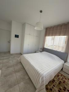 a bedroom with a large white bed and a window at Tala Rivera Paradise in Tala +9 photos
