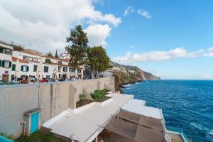 a row of white buildings on the side of the ocean at Barreirinha II Near Old Town With Nice Ocean Views in Funchal