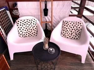 two white chairs and a table on a porch at Georgia Tiny House - Hiperbara Livezeni Mures in Livezeni