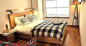 a bedroom with a bed with a checkered blanket and a window at Georgia Tiny House - Hiperbara Livezeni Mures in Livezeni