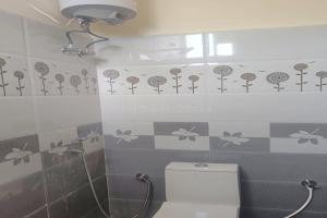 a bathroom with a toilet and flowers on the wall at Dreamscape Rooms - Yelagiri in Yelagiri