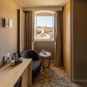 a room with a chair and a table and a window at Grand Hotel Francais in Bordeaux