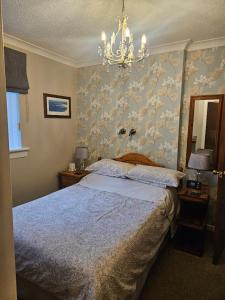 a bedroom with a large bed and a chandelier at Whitecroft B&B in Edinburgh